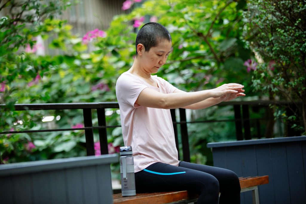 Adult woman with short hair practicing rehabilitation exercises in a park setting.